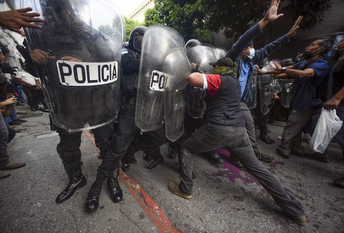 Manifestantes se enfrentan a la policía antidisturbios durante una protesta exigiendo la renuncia del presidente guatemalteco Alejandro Giammattei, el sábado, en la Ciudad de Guatemala.
 · Foto: Orlando Estrada, AFP
