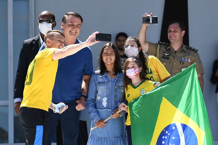 Jair Bolsonaro y su hija Laura posa con seguidores, ayer, frente al Palacio de Planalto, en Brasilia. · Foto: Evaristo Sa, AFP