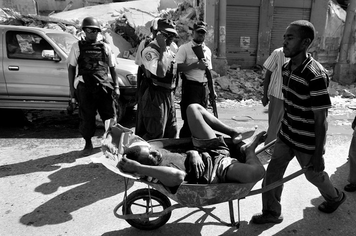 Un hombre herido por un disparo de la Policía haitiana al ser sorprendido saqueando es transportado en una carretilla, ayer, durante los disturbios ocurridos en el centro de Puerto Príncipe.  · Foto: Efe, Orlando Barría