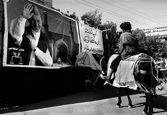 Un niño pasa por delante de un cartel electoral del actual presidente afgano, Hamid Karzai, en Herat.  · Foto: Jalil Rezayee