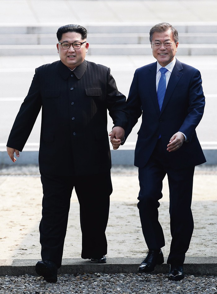 El líder de Corea del Norte, Kim Jong-un, y el presidente de Corea del Sur, Moon Jae-in, ayer, cuando cruzaban la línea de demarcación militar que divide ambos países, en Panmunjom. Foto: S/d de autor, pool, AFP