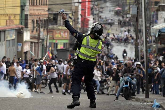 Un policía antidisturbios lanza gases lacrimógenos contra manifestantes durante una protesta de opositores al gobierno del presidente venezolano Nicolás Maduro, el 29 de julio, en el barrio de Catia, en Caracas. · Foto: Yuri Cortez / AFP