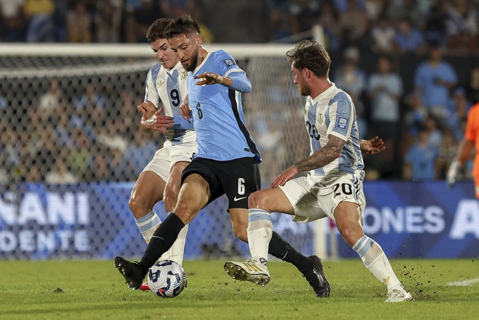 Rodrigo Bentancur (c), de Uruguay, entre los argentinos Julián Alvarez (i) y Alexis Mac Allister, el 21 de marzo, en el estadio Centenario. · Foto: Rodrigo Viera Amaral