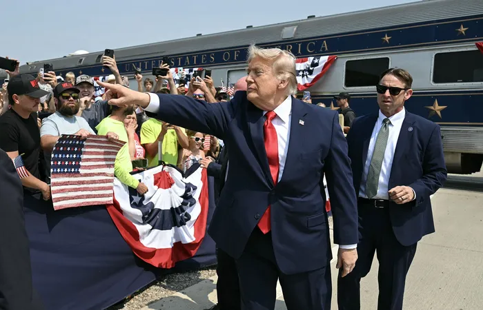 Donald Trump, saluda a los presentes tras llegar a bordo del tren "Freedom250", de camino a la inauguración de la Biblioteca Presidencial Theodore Roosevelt en Medora, Dakota del Norte, el 1º de julio. · Foto: Saul Loeb, AFP