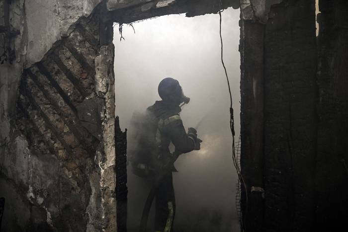 Bomberos extinguen el fuego de una casa alcanzada por cohetes rusos Grad, este miércoles, en el distrito Shevchenkivsky, en Kiev. · Foto: Aris Messinis, AFP