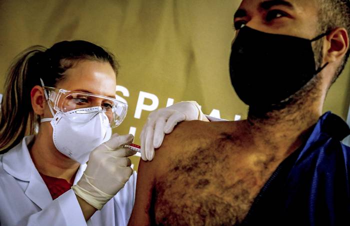 Paulo Roberto Oliveira , trabajador de la salud y voluntario recibe una prueba de la vcuna contra el COVID-19 producida por la compaña Sinovac Biotech, en el Hospital San Lucas, en Puerto Alegre, el 8 de agosto. 

 · Foto: SILVIO AVILA / AFP