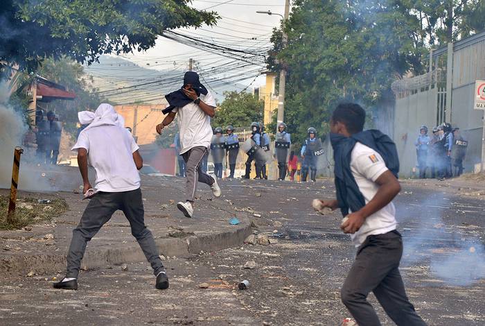 Enfrentamientos entre estudiantes y la policía antidisturbios durante una manifestación en la que exigían la renuncia de Juan Orlando Hernández, en Tegucigalpa, el 1º de julio. · Foto: Orlando Sierra, AFP