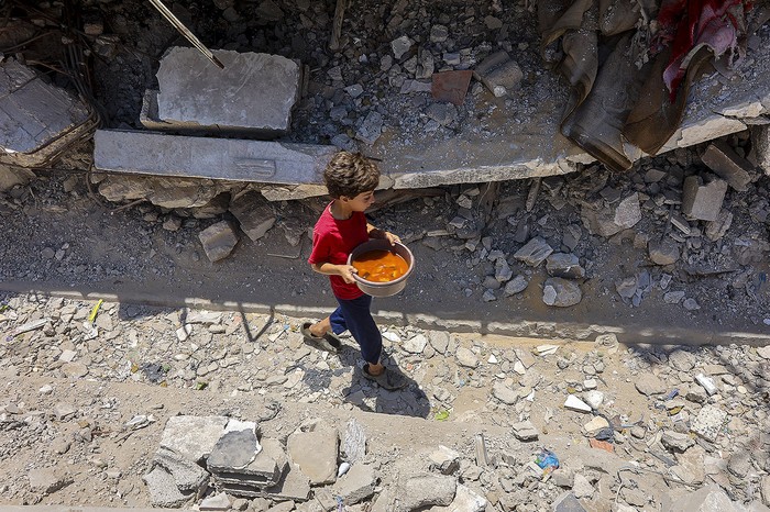 Un niño palestino con comida recibida en un comedor social en el barrio Rimal, en Gaza, el 18 de junio. · Foto: Omar Al-Qattaa, AFP