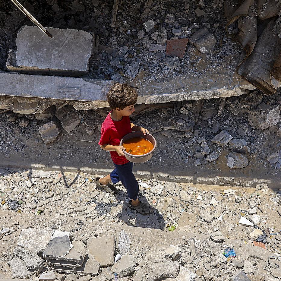 Un niño palestino con comida recibida en un comedor social en el barrio Rimal, en Gaza, el 18 de junio. · Foto: Omar Al-Qattaa, AFP